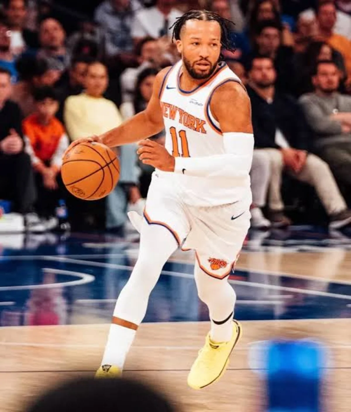Jalen Brunson in a white New York Knicks uniform dribbling the basketball