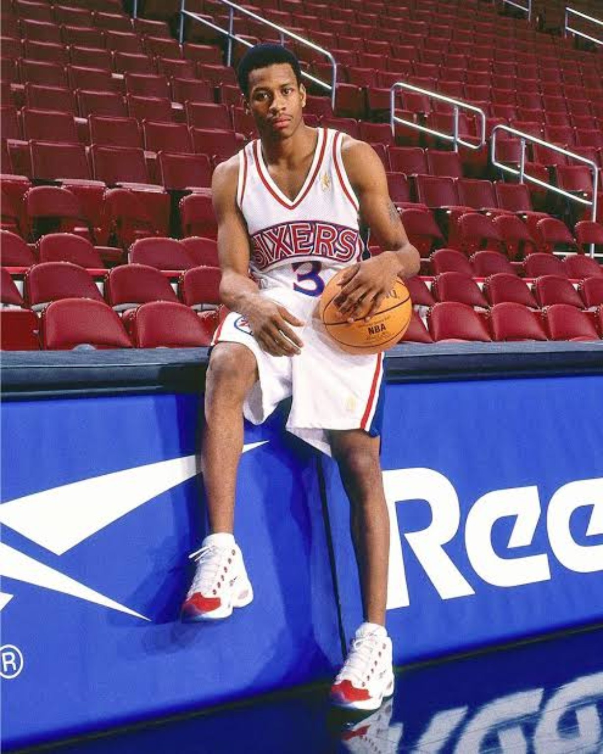 Allen Iverson posing with a basketball in a white Philadelphia 76ers uniform during his rookie season