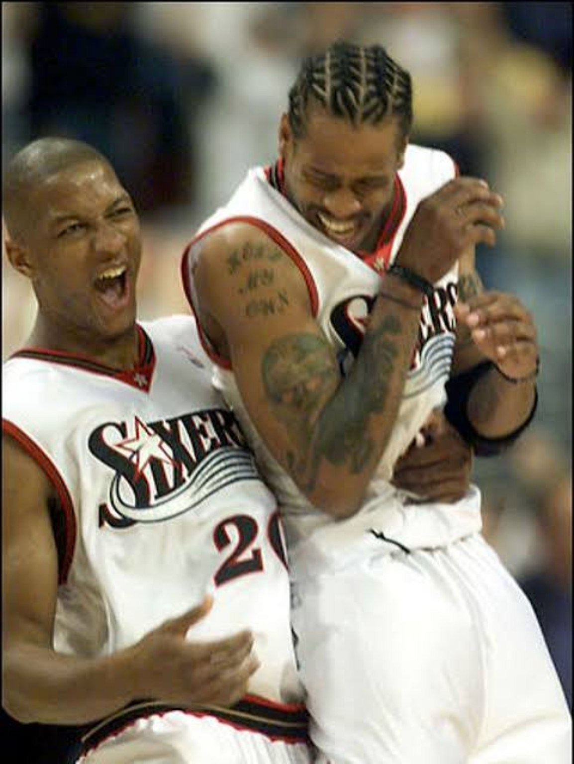 Two Philadelphia 76ers teammates sharing a light moment during the late-1990s era