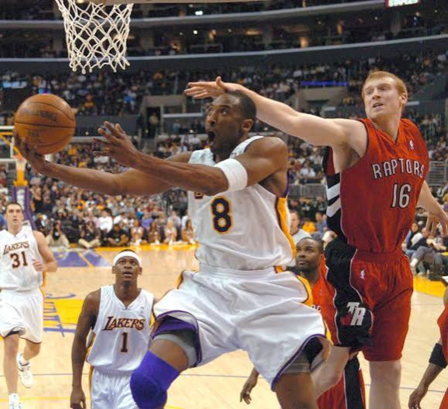 Kobe Bryant in a gold Los Angeles Lakers number 8 uniform rising toward the rim